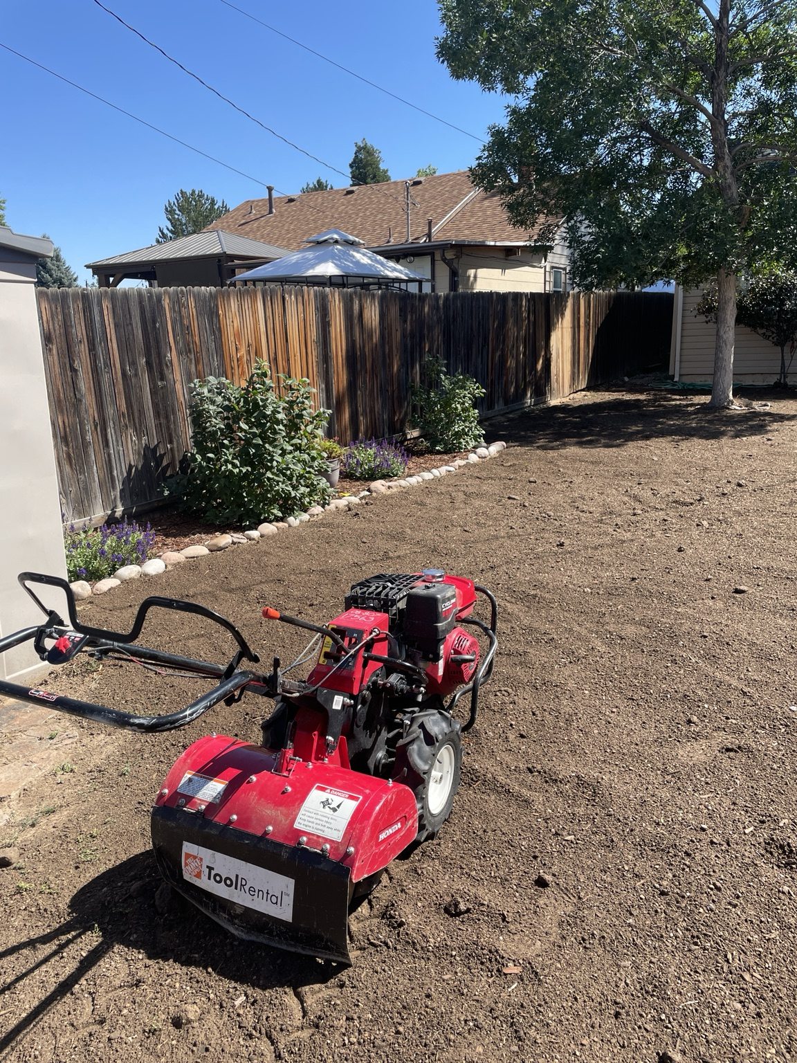 A rental tiller on bare backyard soil