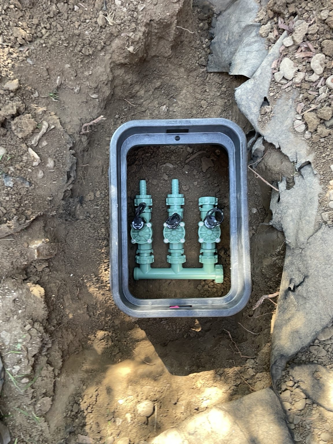 A three-zone irrigation manifold assembled inside the valve box